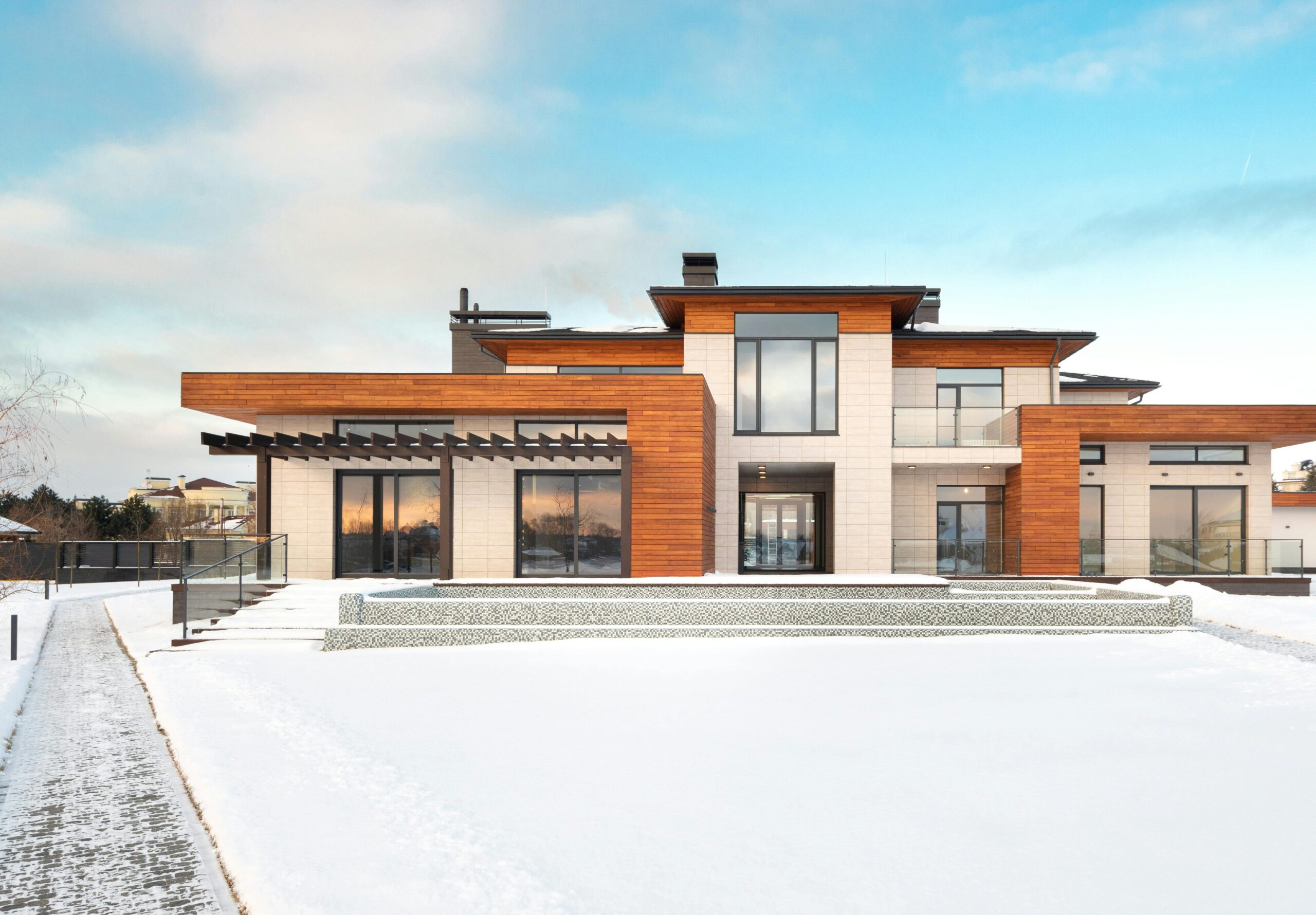 Contemporary house with wooden facade in snowy landscape, ideal for winter real estate.